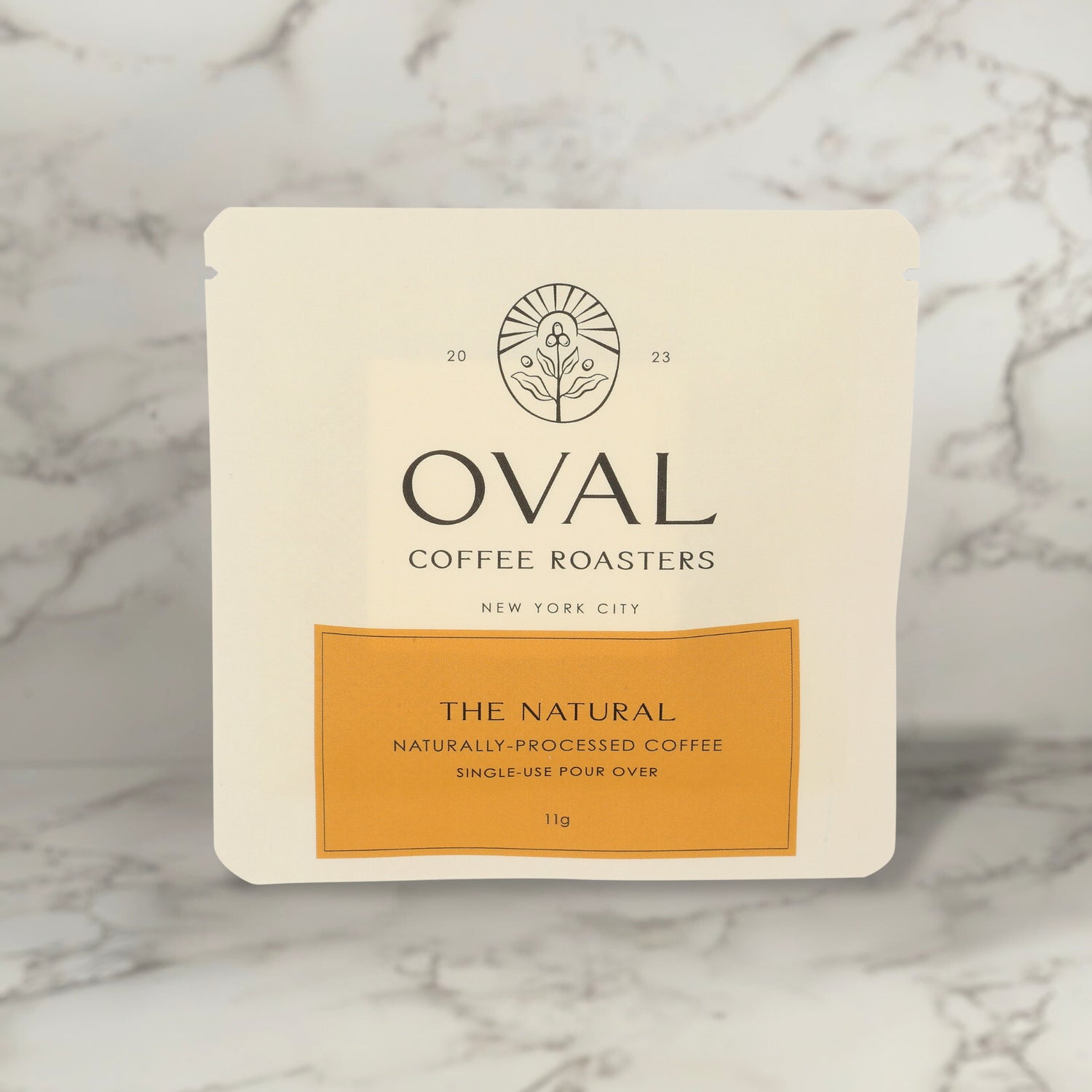 Oval Coffee Roasters The Natural single-serve 11g pour-over drip single use coffee packet — a naturally processed light roast crafted in New York City, highlighting the brand’s focus on women-produced, half-caff, and sustainably sourced coffees with fruit-forward sweetness.