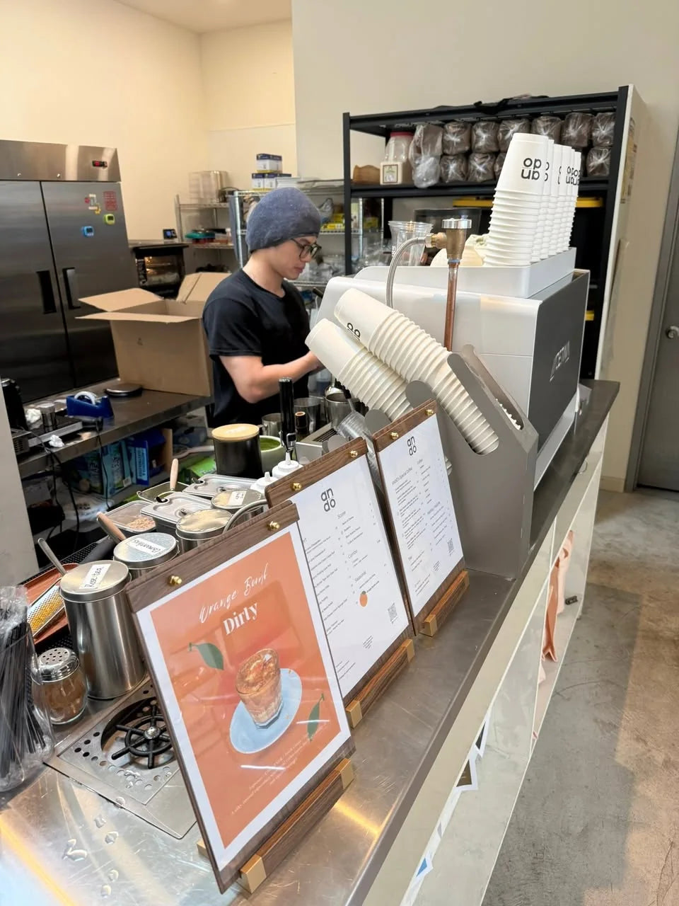 Person preparing service behind a café counter.