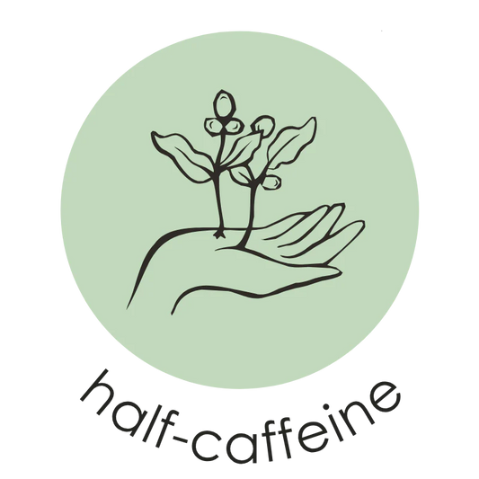 Oval Coffee Roasters Riverside Half-Caf coffee badge with a black line drawing of a hand holding coffee branches inside a pale green circle, with “half caffeine” lettering below on a transparent background.