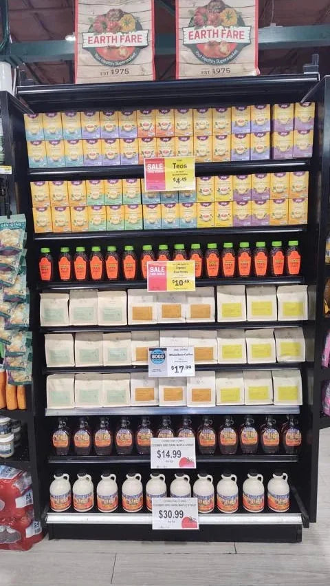 Oval Coffee Roasters whole-bean coffee on an Earth Fare supermarket endcap with a buy one, get one free offer, alongside Yogi Tea, honey and maple syrups, October 2026.