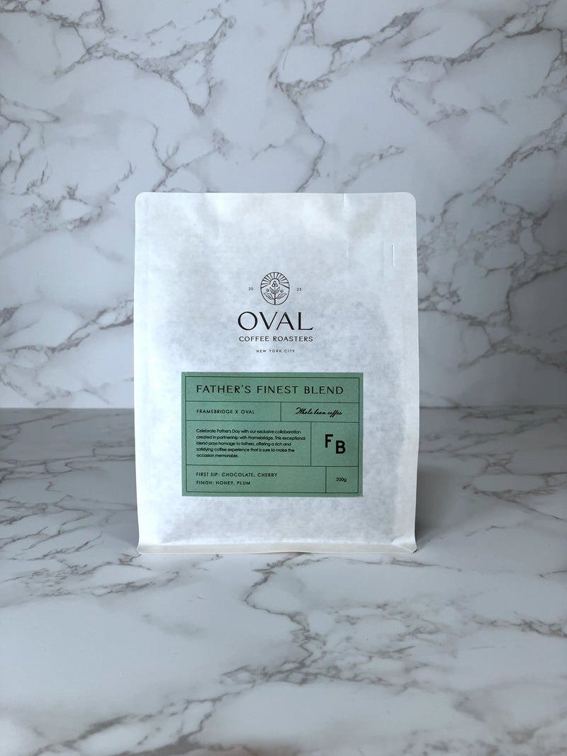 Oval Coffee Roasters Father's Finest Blend whole-bean coffee bag from the Framebridge collaboration, with a green label on a white pouch against a gray-veined marble background.